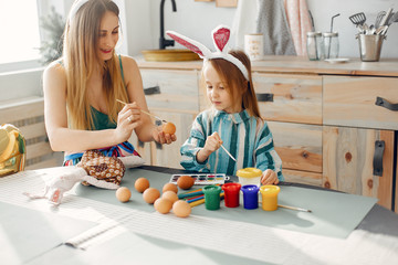 Naklejka premium Mother and daughter paint eggs. Family in a kitchen. Preparing for Easter
