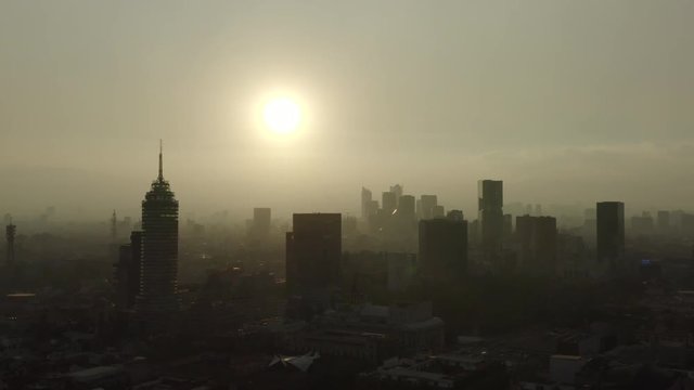 Aerial shot of the Mexico City center skyline, with sun backlight.