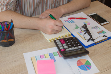 Businessman writing in a notebook. A businessman doing some paperwork using his calculator