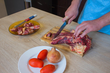 hands of a butcher cutting slices of raw meat off a large loin. Preparing meal