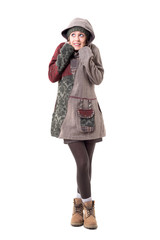 Cute young stylish woman in hoodie and winter coat freezing and looking up. Full body isolated on white background. 