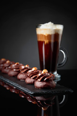  Chocolate dessert with hazelnut and coffee with cream on a black background.