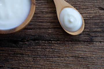 Natural homemade plain organic yogurt in wooden bowl and wood spoon on wood texture background