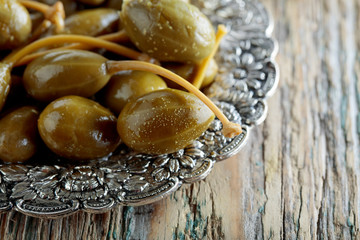 Pickled caper berries in metal dish .