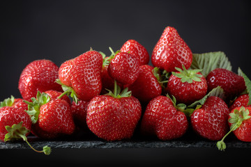 Fototapeta na wymiar Ripe strawberries with green leaves on a black background.