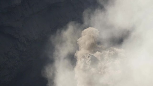 Slow motion ash clouds rising from Bromo active volcanic crater viewed from high angle.