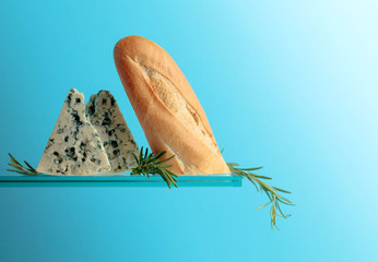 Blue cheese with bread and rosemary on a blue background.