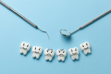 White tooth with caries on blue background  and dentist tools mirror, hook.