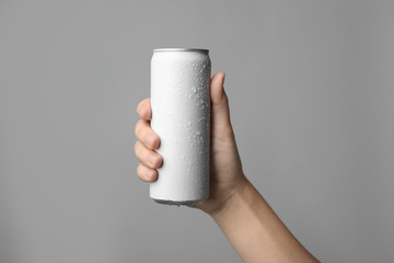 Woman holding aluminum can with beverage on grey background, closeup. Space for design - obrazy, fototapety, plakaty
