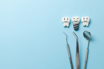 Healthy white teeth and implants are smiling on blue background and dentist tools mirror, hook. Copy space for text.