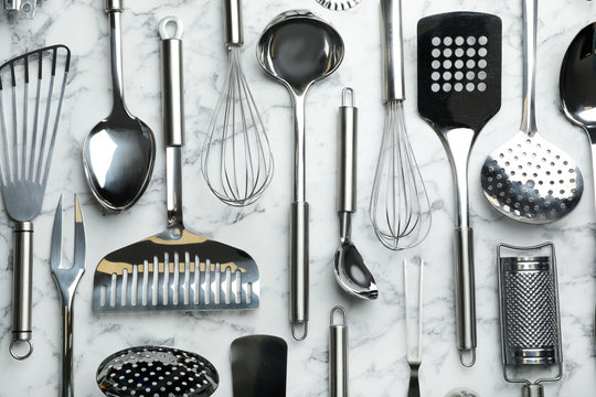 Different kitchen utensils on marble background, flat lay