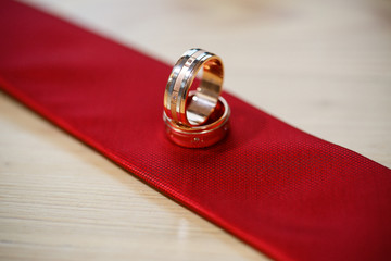 Gold wedding rings lie on a tie