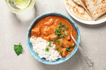 Delicious butter chicken with rice in bowl served on grey table, top view