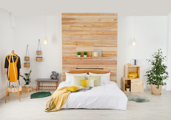 Stylish room interior with comfortable bed near wooden wall