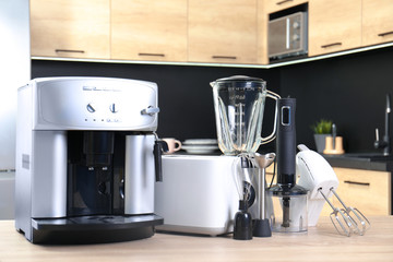 Modern domestic appliances on wooden table in kitchen