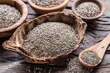Chia seeds in different dishes on old wooden table. Top view.