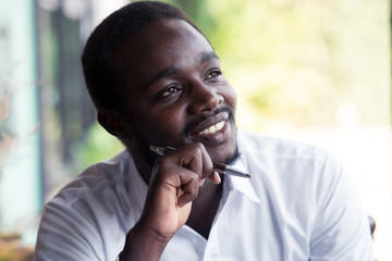 African man thinking and looking with holding a pen.