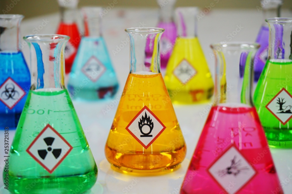 Wall mural many of erlenmeyer flask with colorful solution and variety type of chemical hazard warning symbols 