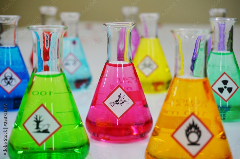 Wall mural many of erlenmeyer flask with colorful solution and variety type of chemical hazard warning symbols 