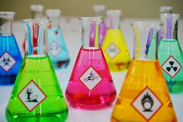 Many of Erlenmeyer flask with colorful solution and Variety type of chemical hazard warning symbols...