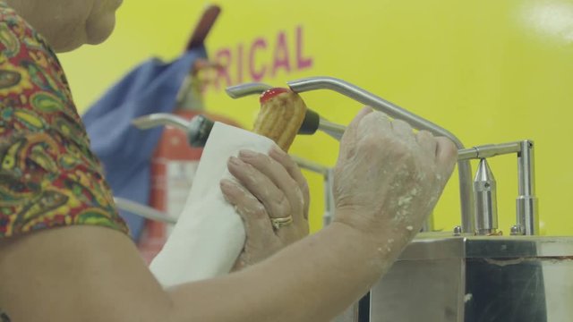 A woman stuffing farturas (portuguese name of a cultural food) in deep oil at Portugal summer village festivals