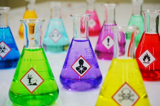 Many of Erlenmeyer flask with colorful solution and Variety type of chemical hazard warning symbols labels. Focus on Serious health hazard sign,symbol.