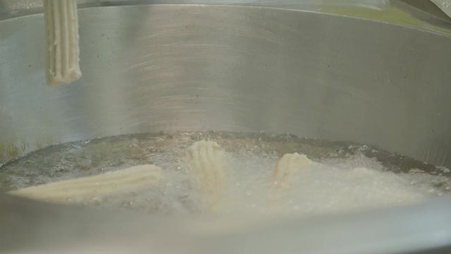 A woman frying and chopping farturas (portuguese name of a cultural food) in deep oil at Portugal summer village festivals