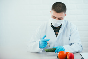 lab technician in lab coat and gloves colitis nitrates and GMO in cucumber on white background in...