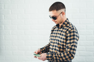 young handsome man in sunglasses with a wad of money in his hands