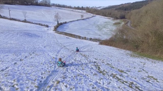 Arial view of two girls sledging in the snow in the Forest of Dean, Gloucestershire.