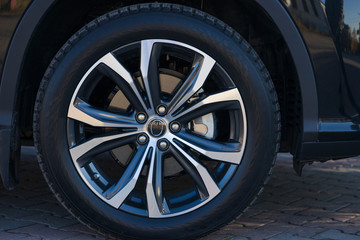 wheel of a black car close up on a sunny day.