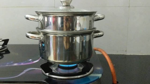 A steam cooking vessel (cooker) on a gas stove cooking idly. A south Indian delicacy.