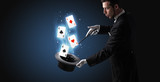 Magician with white gloves conjuring playing cards from a cylinder with magic wand