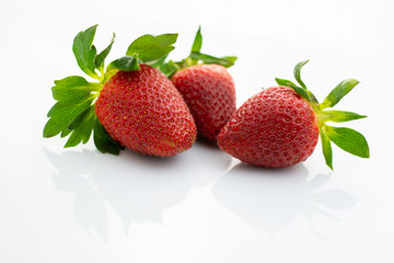 Group of red strawberries with green leaves on white background