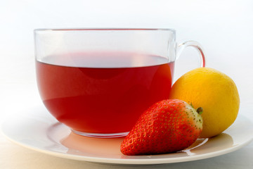 Glass cup of hot aromatic red tea with strawberry and lemon