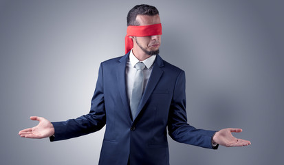 Covered eye, indecisive businessman standing blind in front of a wall