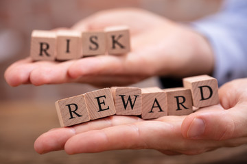 Businessman Holding Risk And Rewards Blocks