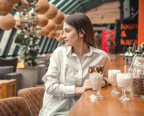 Beautiful Young girl drinking milk chocolate cocktail in a cafe