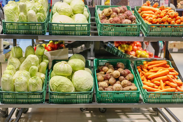 Crates with ripe fresh cabbage, carrots and beetroots on shelves