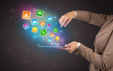 Hand holding tablet and application icons falling inwards
