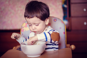 Fototapeta premium The boy eats himself from the plate. An independent child. The child eats
