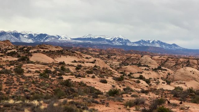 the desert in moab, utah with a backdrop of snow capped mountains making it a perfect picturesque panaromic view