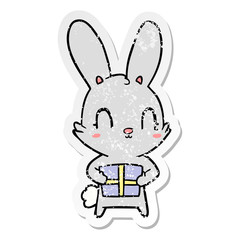 distressed sticker of a cute cartoon rabbit with present