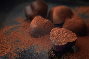Chocolate candy in the form of hearts sprinkled with cinnamon on a dark background