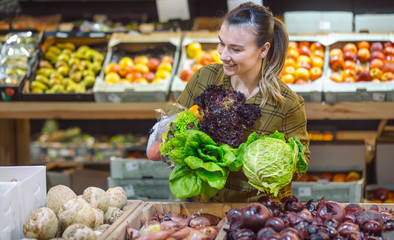 Woman in the supermarket. Beautiful young woman shopping in a supermarket and buying fresh organic vegetables