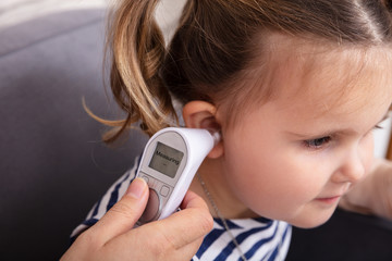 Hand Checking Girl's Ear With Digital Thermometer