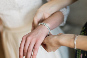 Obraz na płótnie Canvas bride putting on luxury bracelet on hand in the morning, getting ready.