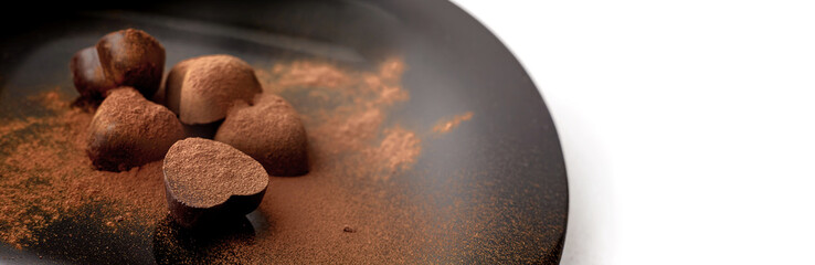 Chocolate candy in the form of hearts sprinkled with cinnamon on a dark background. Place for your text