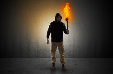 Ugly scary man with burning flambeau walking in an empty space