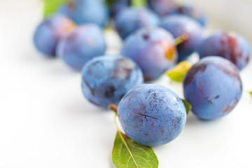 Plums with green leaves on white background